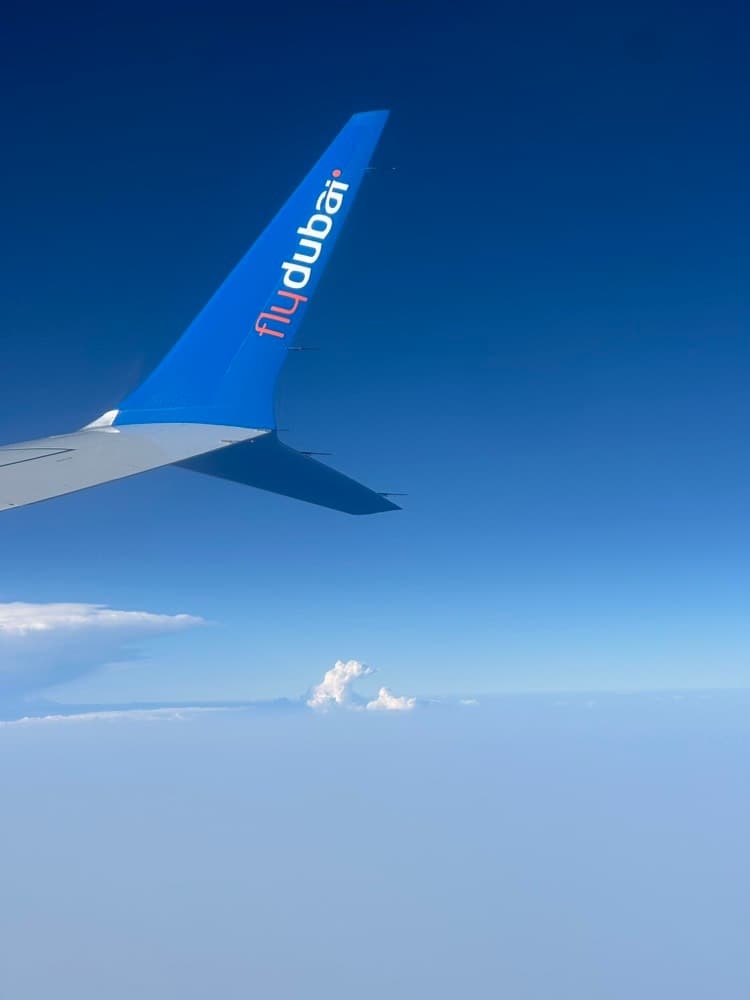 a flydubai wingtip over a sea of clouds, seen from the window seat